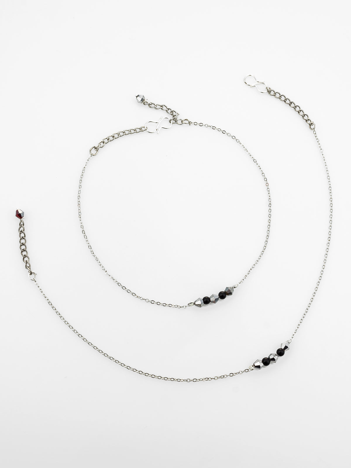 A delicate silver chain anklet with small black beads and a tiny red accent bead, displayed on a clean white background.