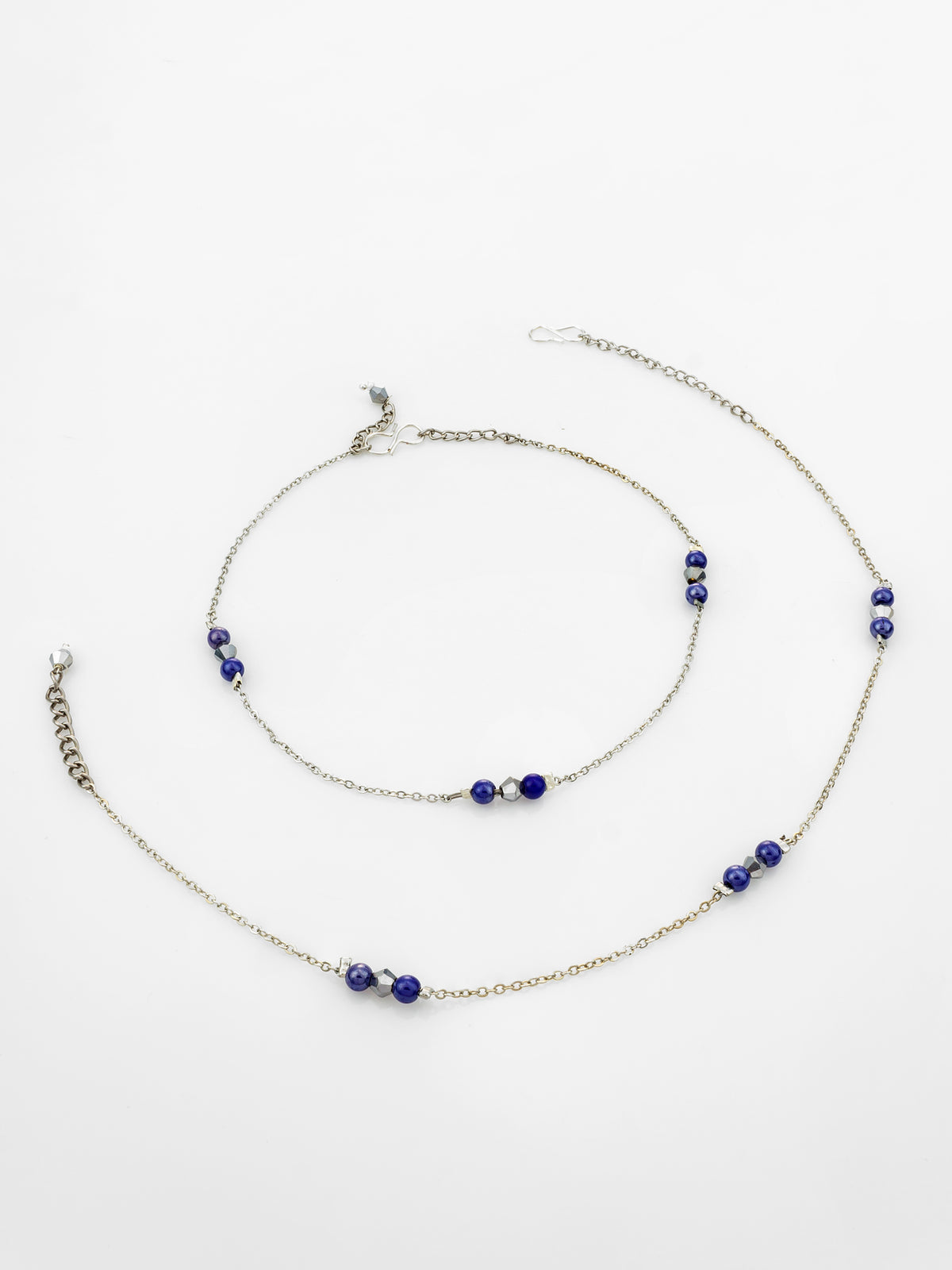 A silver-toned beaded anklet and matching anklet chain set, featuring deep blue beads and small white accent beads, displayed on a clean white background.