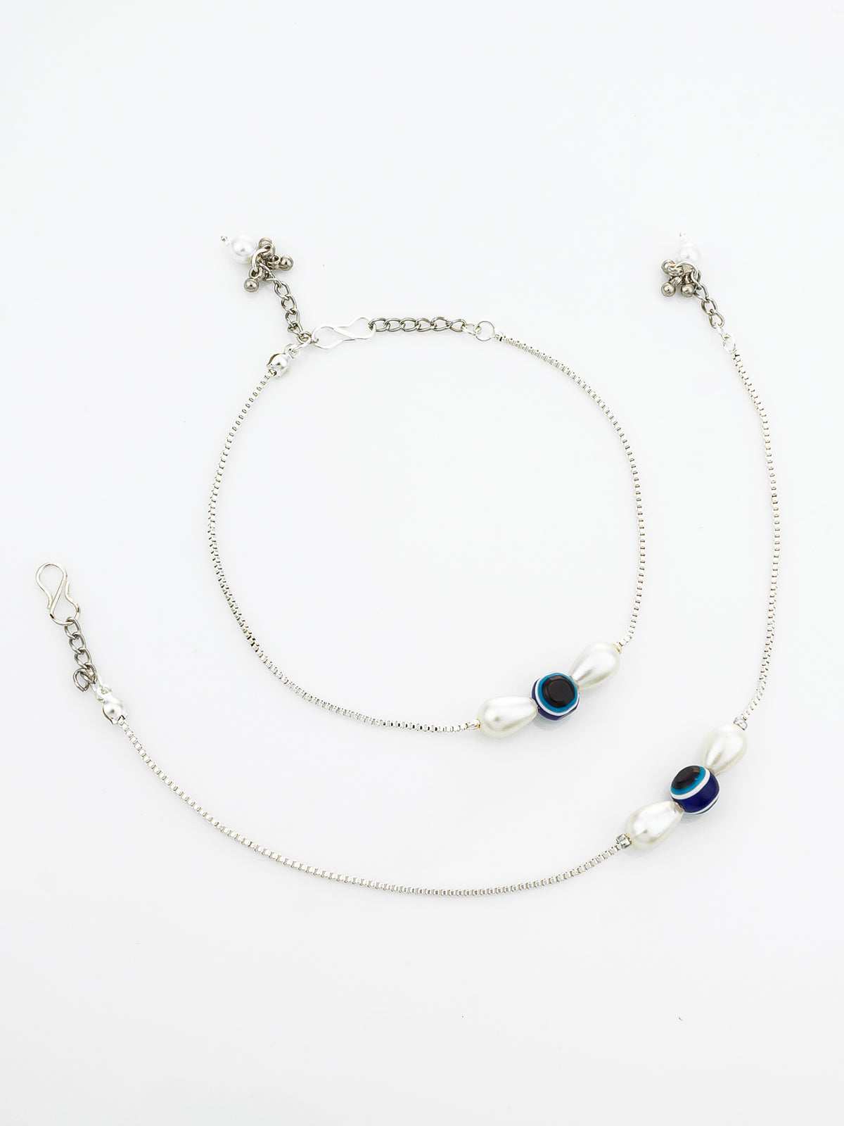 A pair of silver chain anklets with white pearl-like beads and blue evil eye charms, displayed on a clean white background.