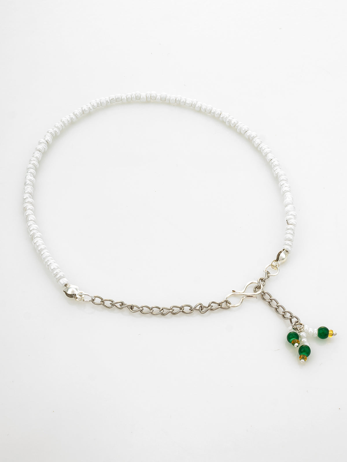 A white beaded necklace with a silver-tone chain extender and a small dangling charm featuring green beads and gold accents, displayed on a clean white background.