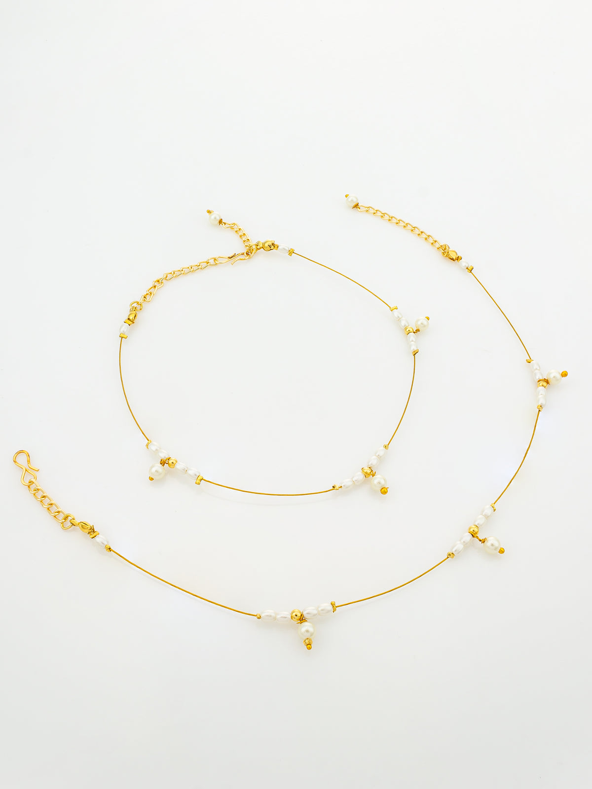 A delicate gold chain anklet with small white beads and tiny gold charms, displayed on a clean white background.