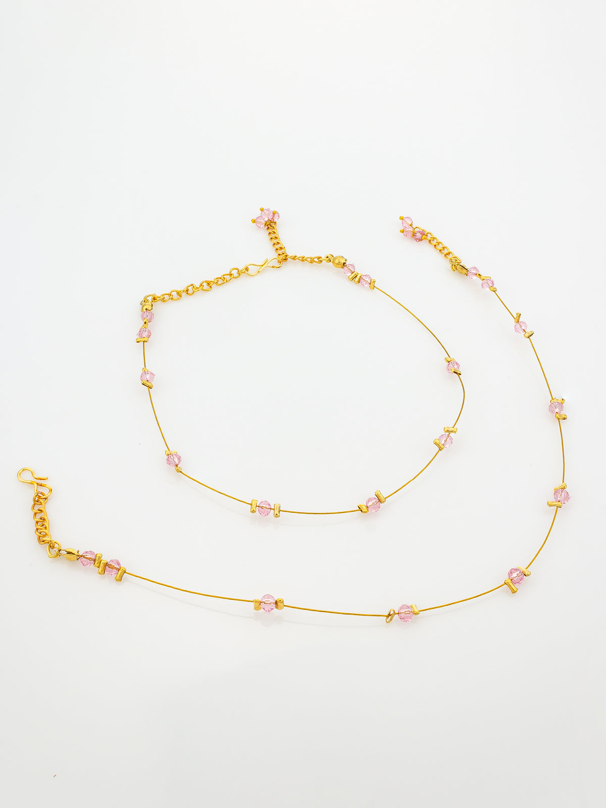 A delicate gold chain anklet featuring small, faceted light pink beads spaced along the chain, displayed on a clean white background.