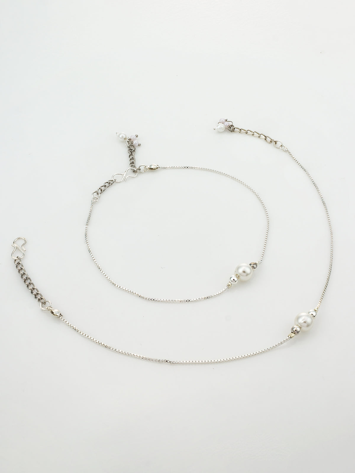 A delicate silver-toned anklet featuring a fine chain, a small silver bead, and two white pearl-like beads, displayed on a clean white background.