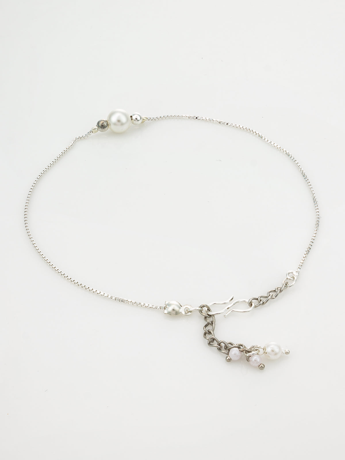 A delicate silver chain anklet featuring a single white pearl bead, a small silver bead, and a dangling charm with two small pearls and silver links, displayed on a clean white background.