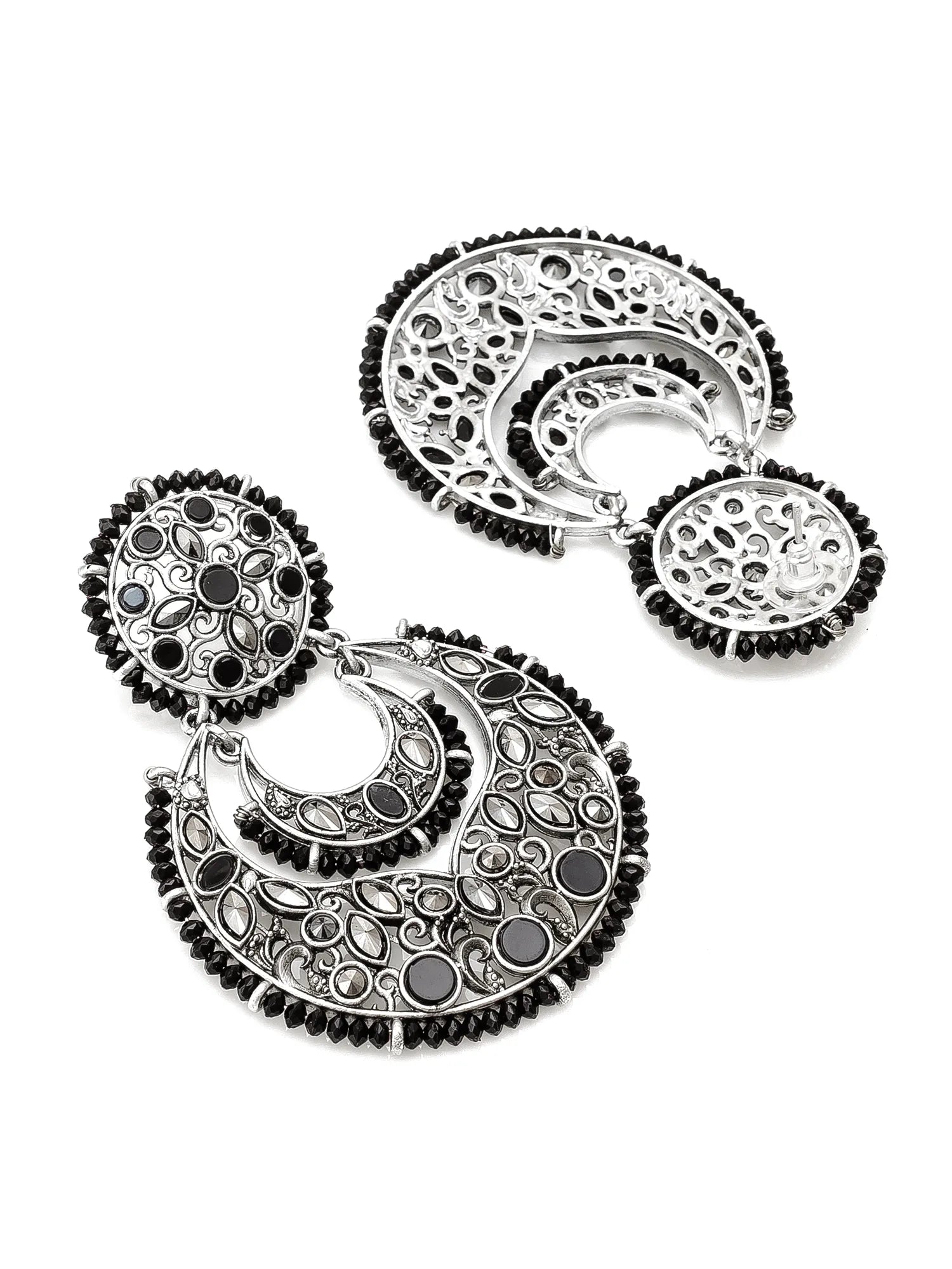 A pair of large silver-toned crescent-shaped statement earrings with intricate filigree cutouts, black circular stones, and rows of small black beads along the edges, displayed on a clean white background.