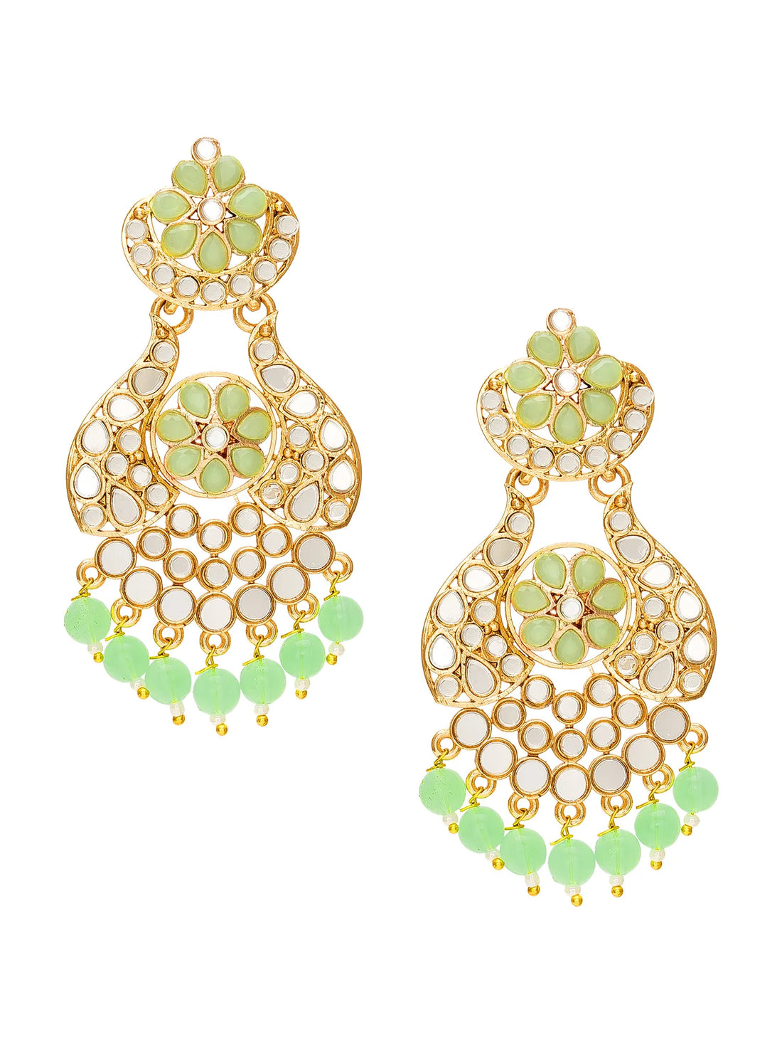 A pair of ornate gold-toned Indian jhumka earrings embellished with green stones and white inlay, displayed on a carved wooden box with draped green fabric in the background.