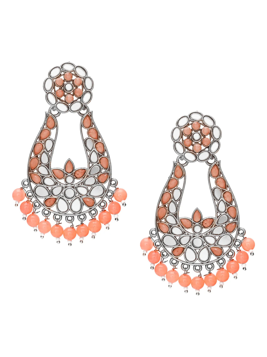 A pair of ornate silver-toned chandelier earrings embellished with white stones, peach-pink teardrop beads, and orange bead fringe, displayed on a carved wooden box with green fabric in the background.