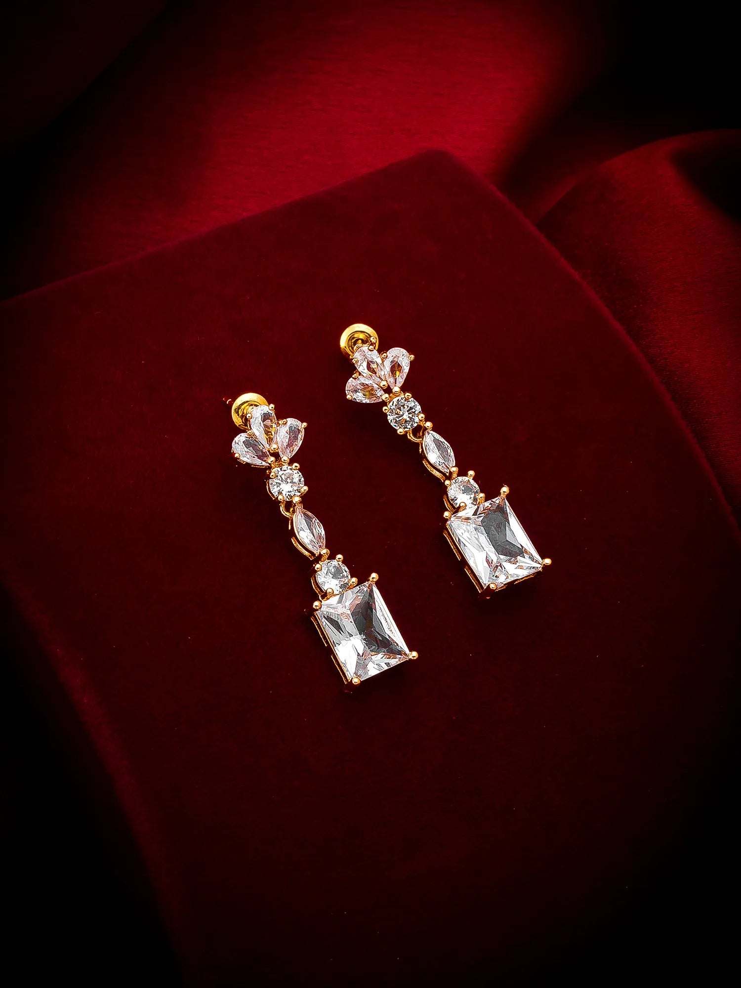 Pair of diamond earrings on a red fabric background