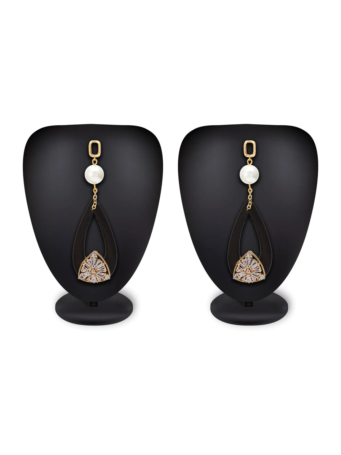 A pair of black teardrop-shaped drop earrings with gold-tone posts, white pearl beads, and a clear rhinestone floral design at the bottom, displayed on a turquoise background with a white plate and pale flowers.