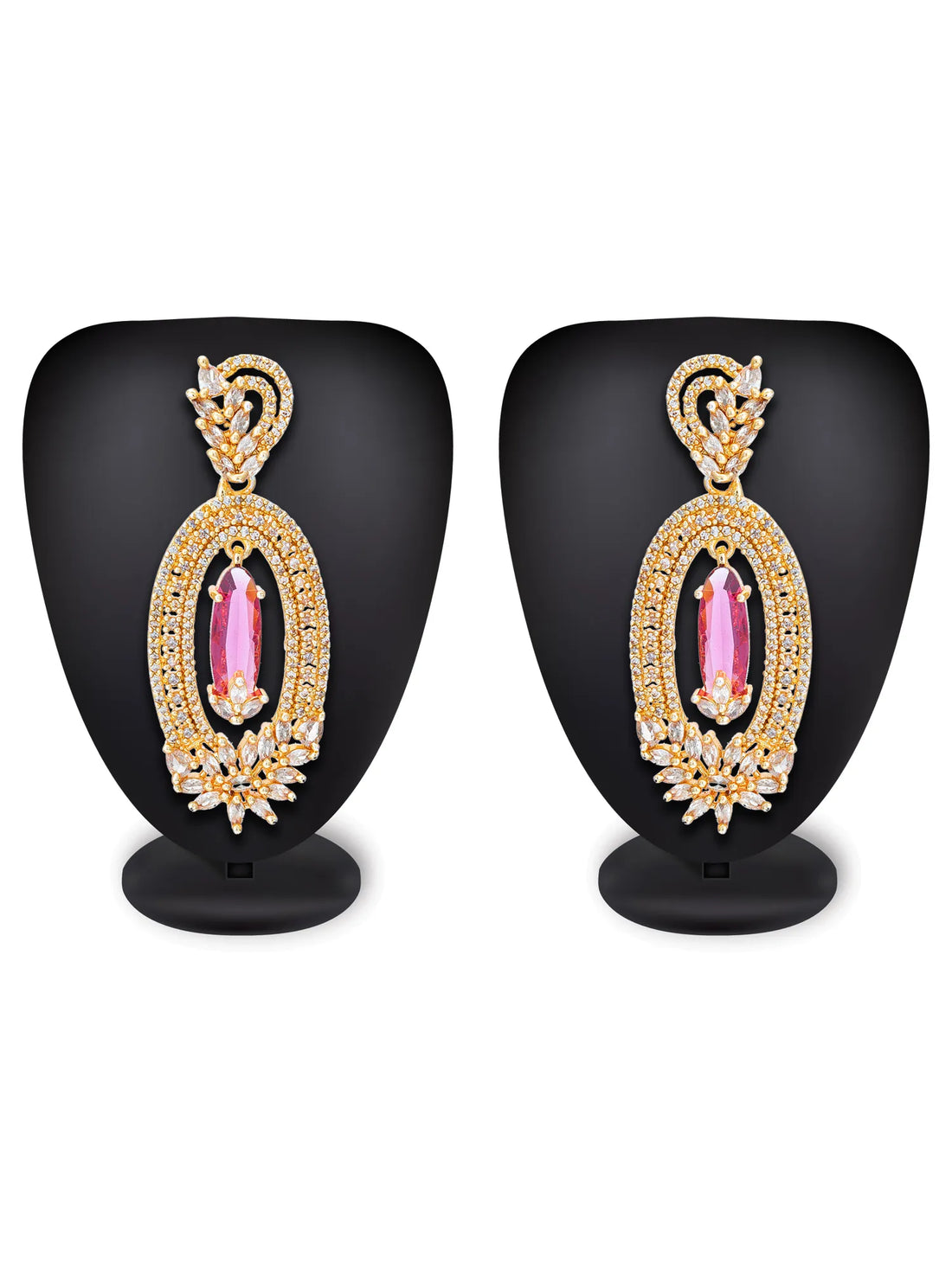 A pair of ornate gold-toned dangle earrings with marquise-cut deep red gemstones and pavé-set clear stones, displayed on a dark green background with draped red satin fabric.