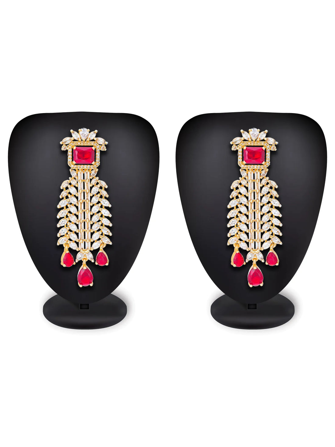 A pair of gold-toned traditional Indian chandelier earrings with rectangular red gemstones and teardrop red drops, embellished with small clear stones, displayed on a dark green background with a draped red fabric.