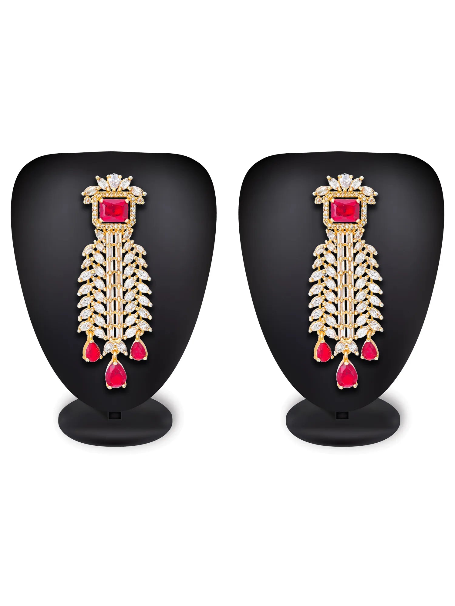 A pair of gold-toned statement earrings with a central square red gemstone, a feather-like drop of clear stones, and three dangling red teardrop gems, displayed on black mannequin busts against a white background.