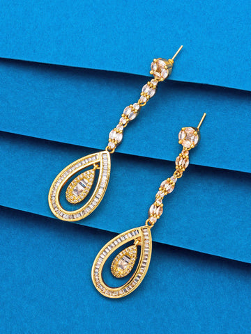 A pair of gold teardrop dangle earrings with clear rhinestone accents, displayed on a textured blue background.