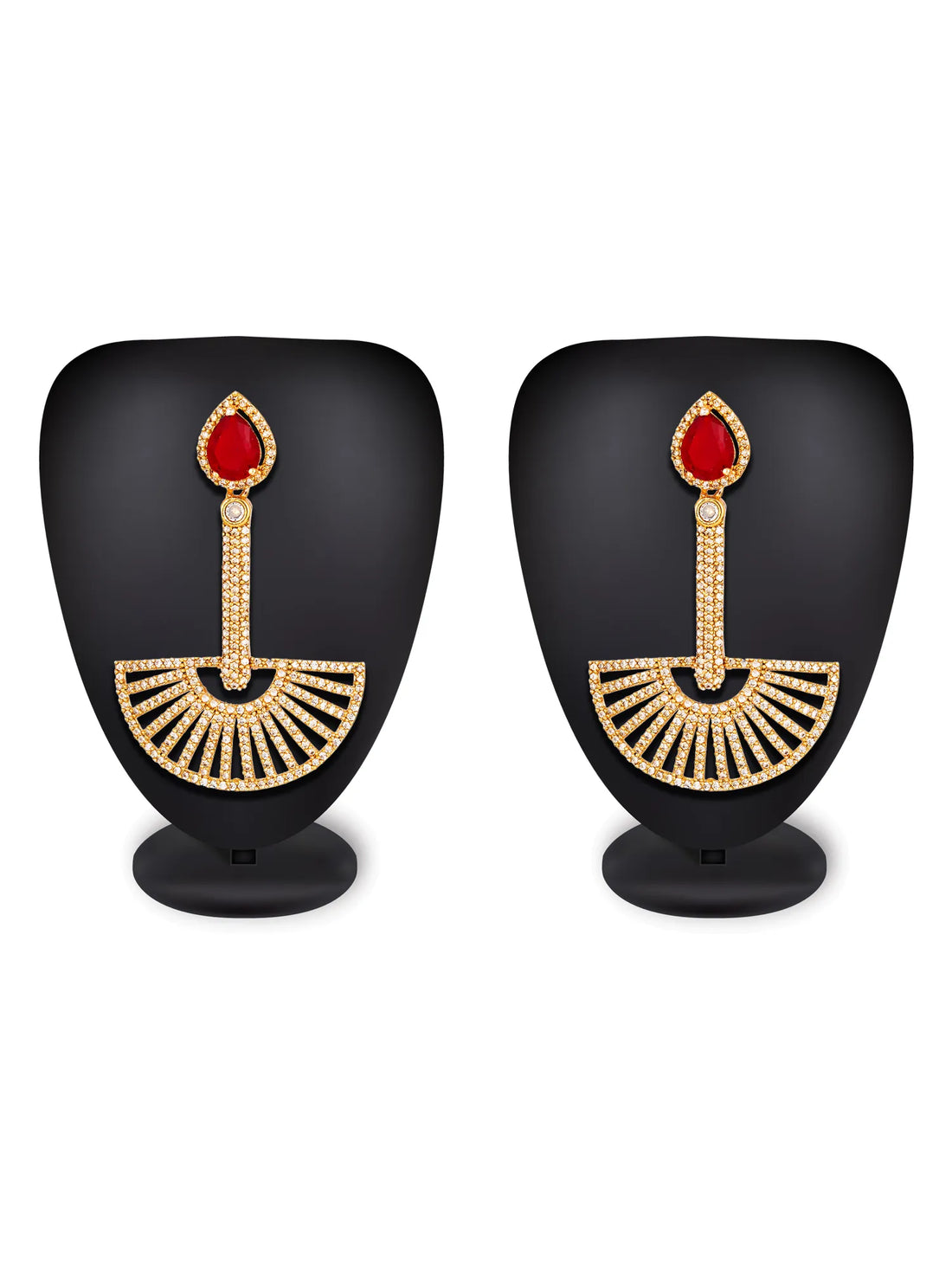 A pair of gold-toned dangle earrings with teardrop-shaped red gemstones and fan-shaped pavé-set details, displayed on a textured blue background.
