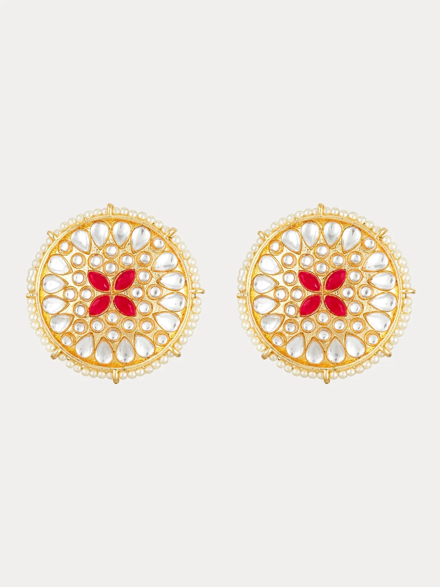 A pair of gold-plated circular earrings with intricate white stone filigree and a central red floral motif, shown on a light gray background.