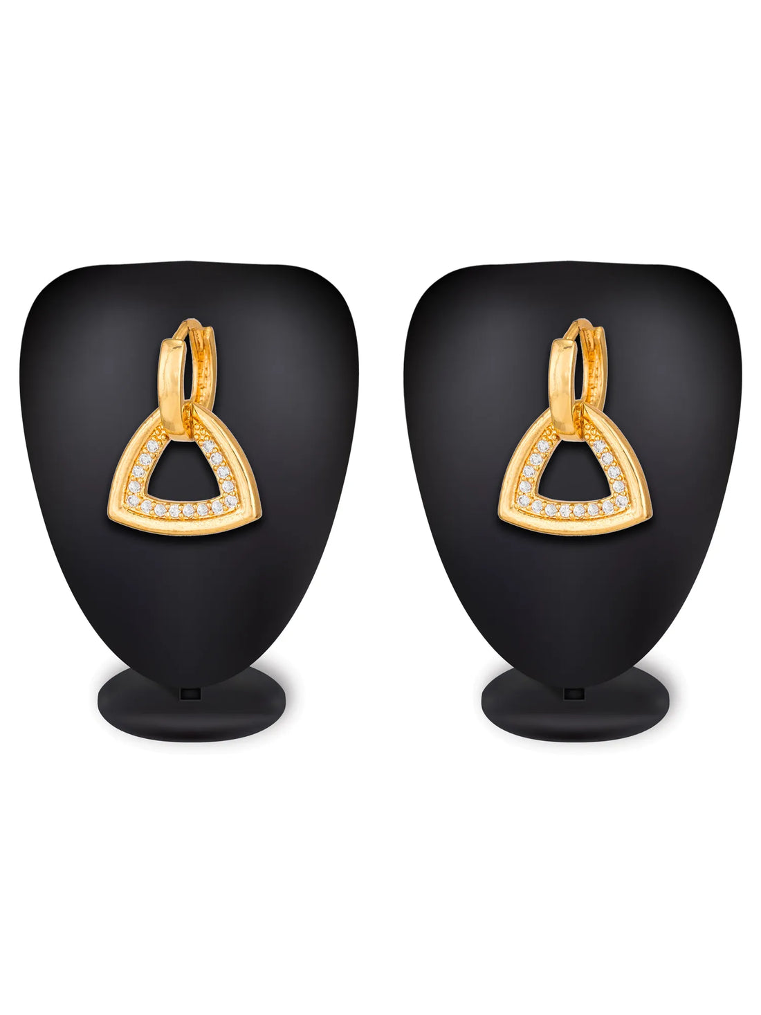 A pair of gold triangular hoop earrings with small clear stones along the front edges, displayed on a neutral taupe surface with a yellow leaf in the top right corner.