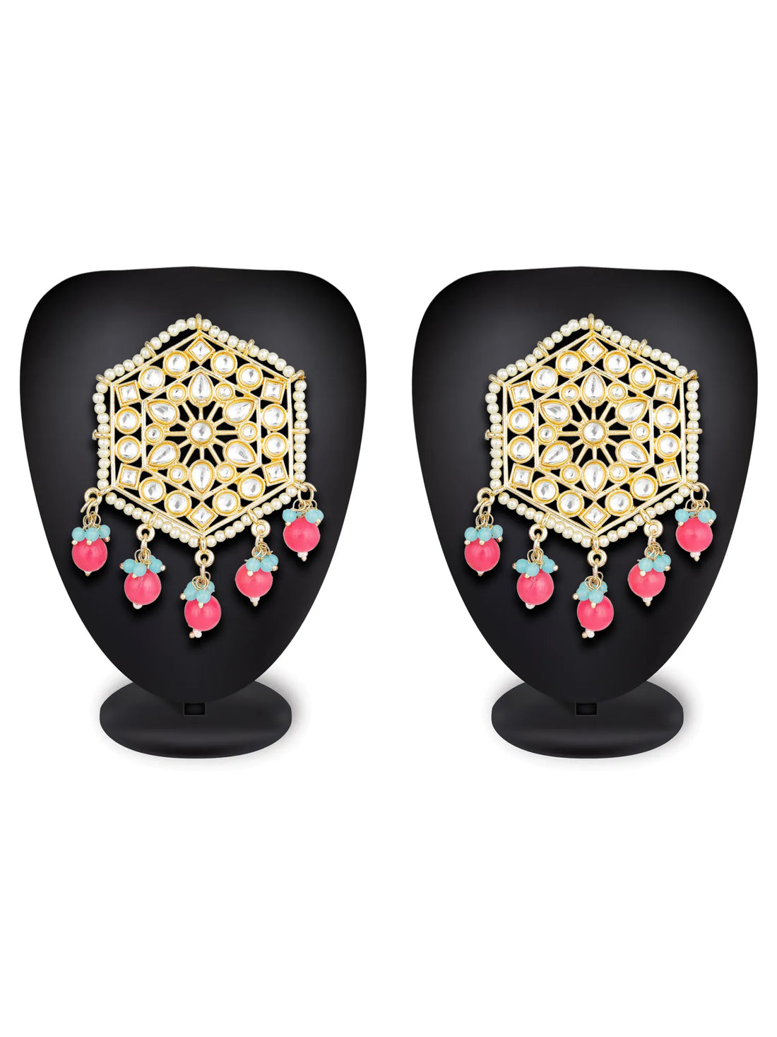 A pair of gold-toned geometric dangle earrings with white stones, green beads, and pink bead drops, arranged on a dark teal background.
