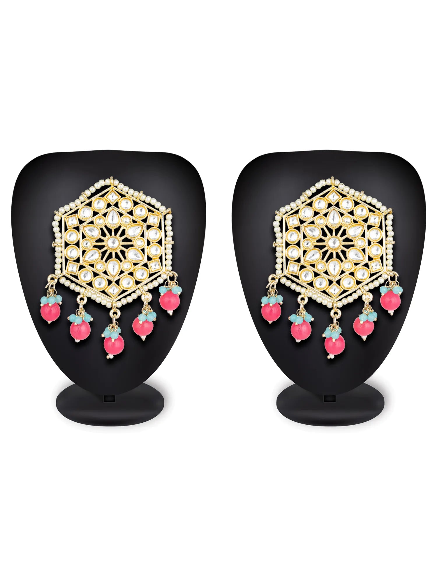 A pair of gold-toned traditional Indian earrings with intricate filigree work, clear stones, and dangling pink and light blue bead accents, displayed on black mannequin busts against a white background.