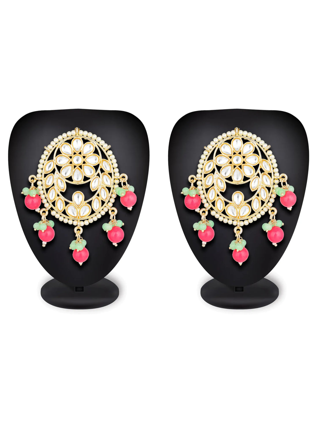 A pair of gold-toned Indian chandbali earrings with white inlay stones, pink bead drops, and green stone accents, displayed on a dark teal background.