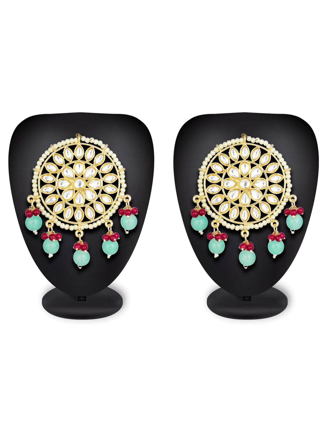 Ornate gold earrings with turquoise and red beads on a teal background