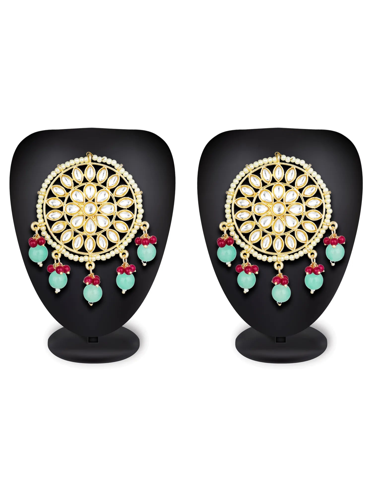A pair of gold-plated Kundan earrings with white stones, mint green bead drops, and red floral accents, displayed on black mannequin stands against a white background.