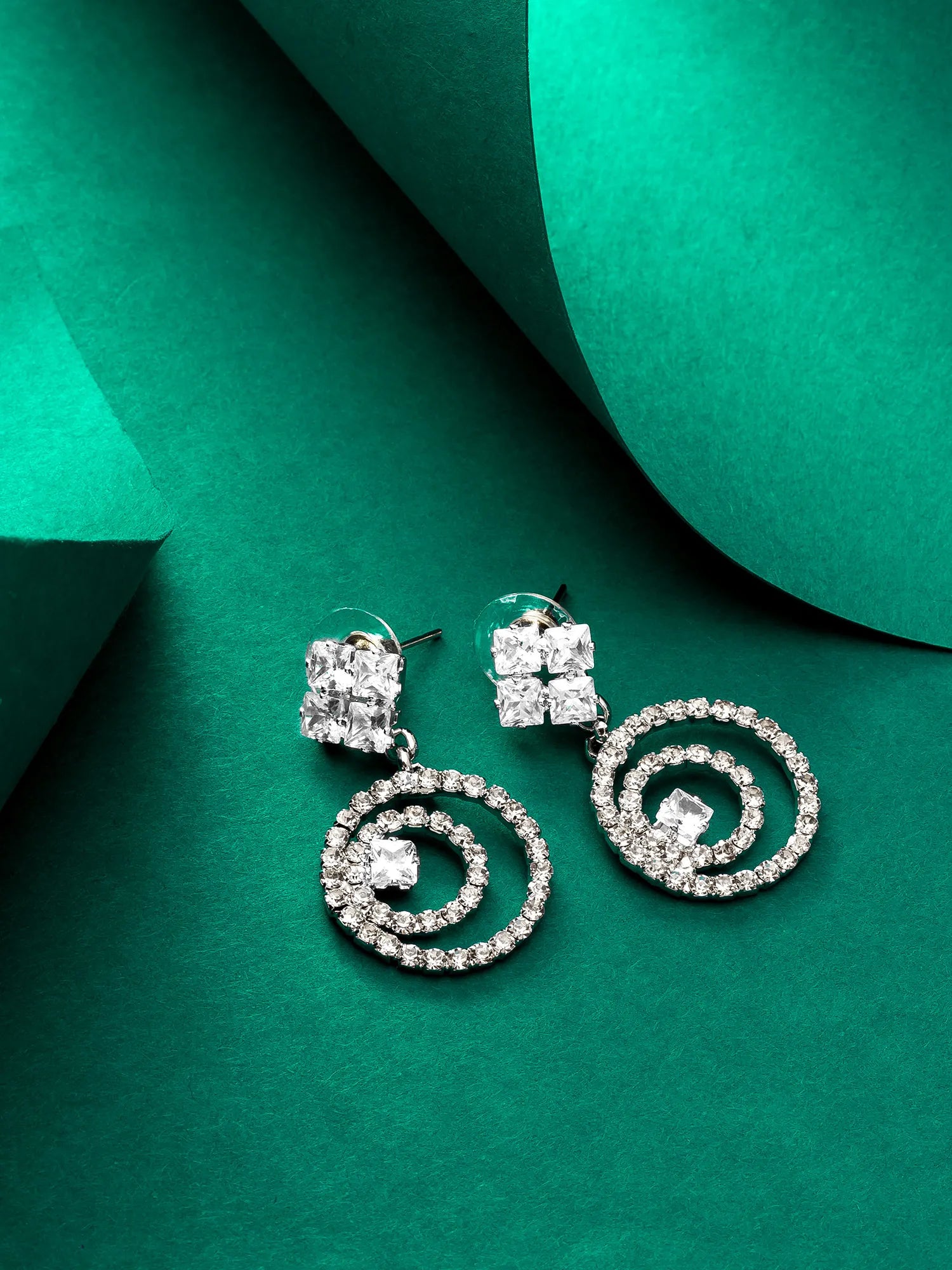 Silver spiral earrings on a green textured background