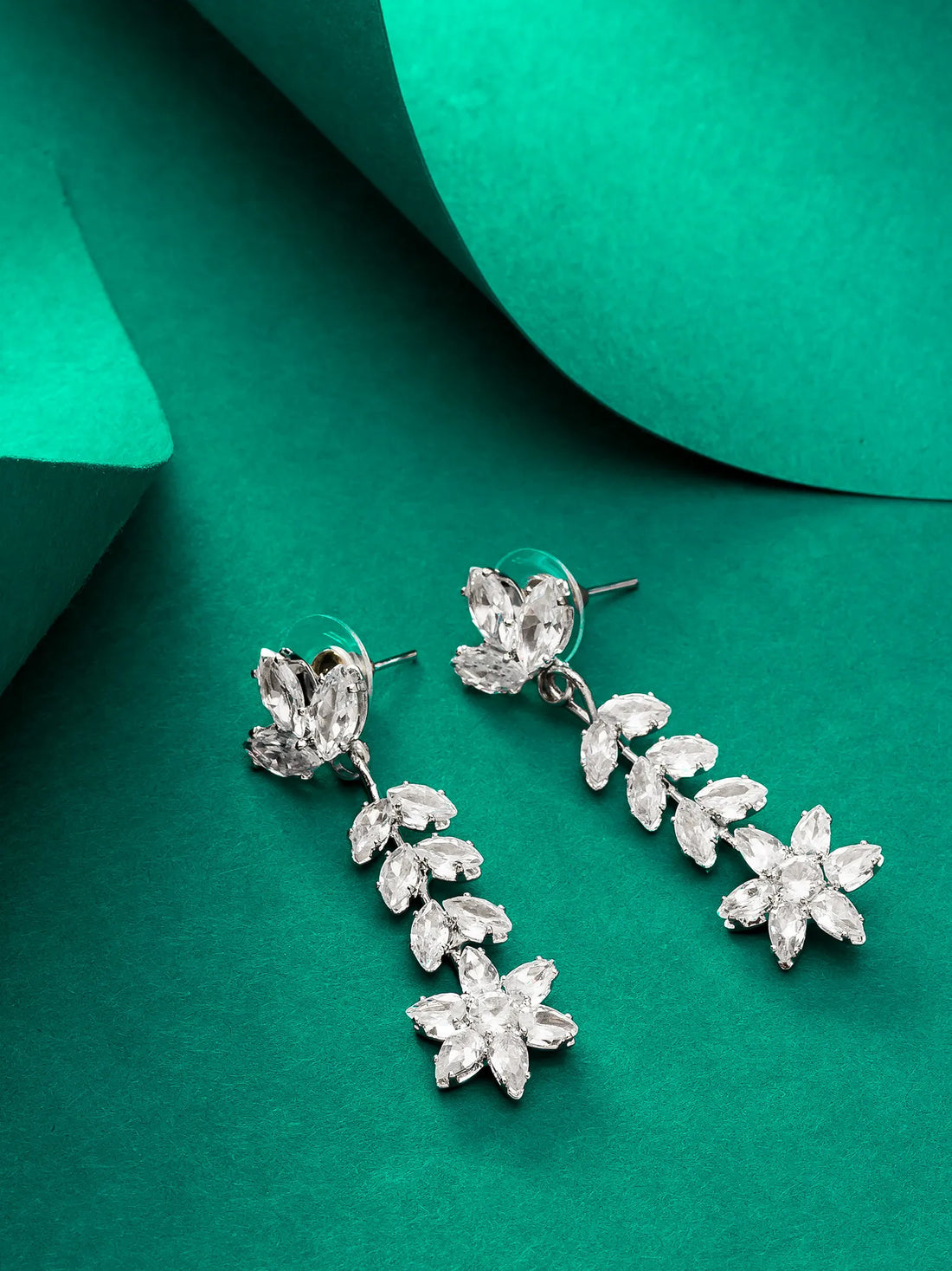 Silver floral earrings on a green background