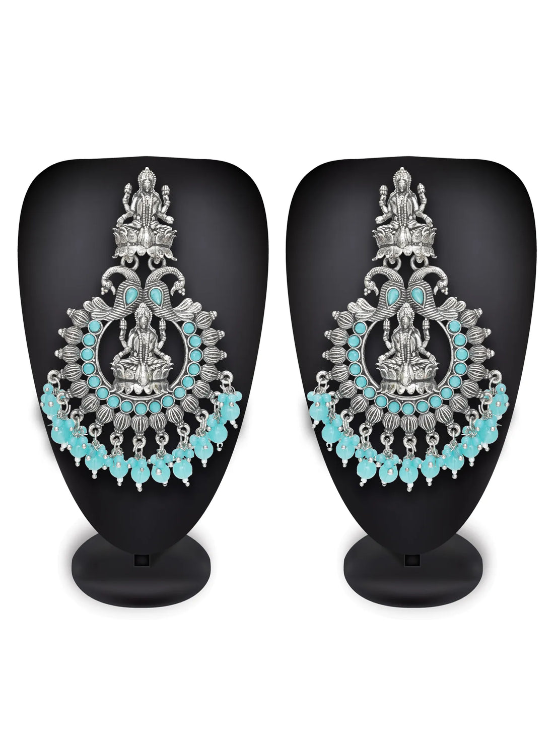Ornate earrings with turquoise stones on a dark fabric background