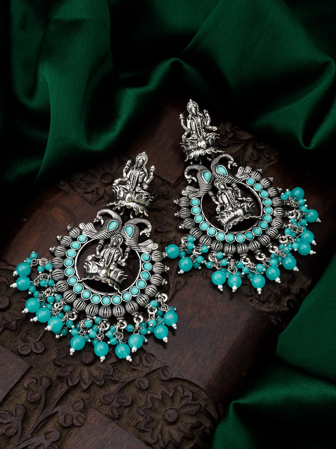 Ornate earrings with turquoise stones on a dark fabric background