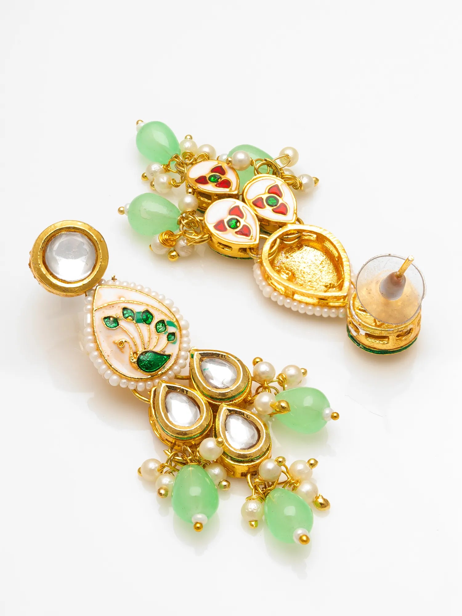 A pair of ornate gold-plated Indian Kundan earrings decorated with green jade-like beads, white faux pearls, and red and green enamel details, displayed on a clean white background.