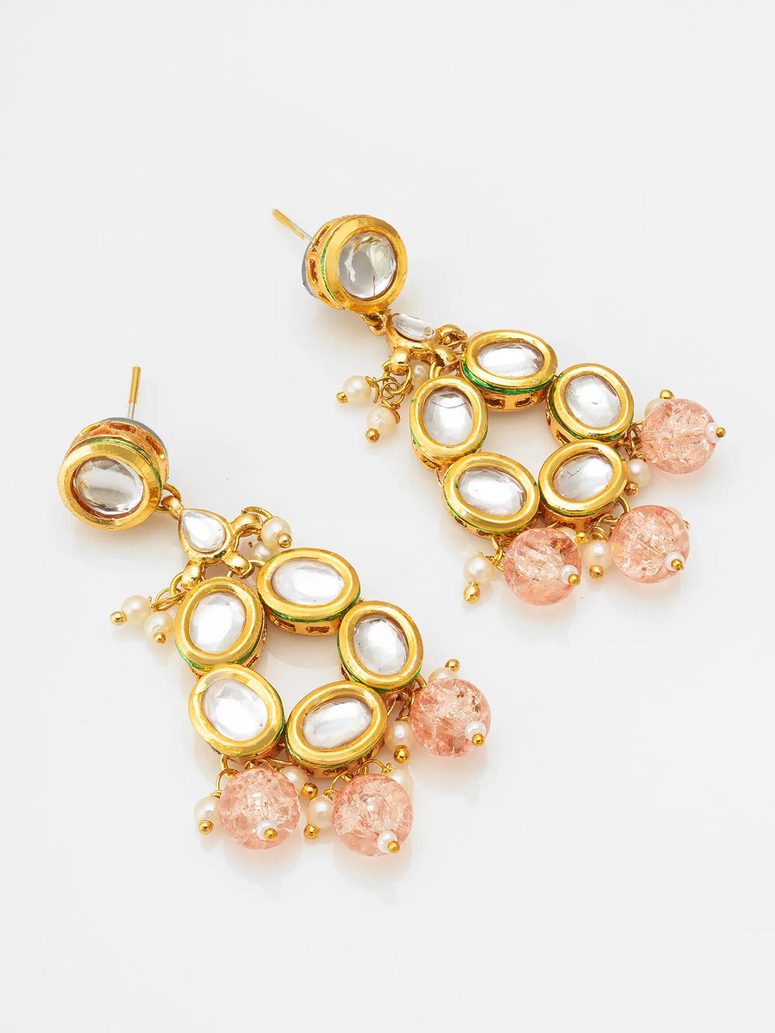 Gold and pink earrings on a pink surface with a red and gold background