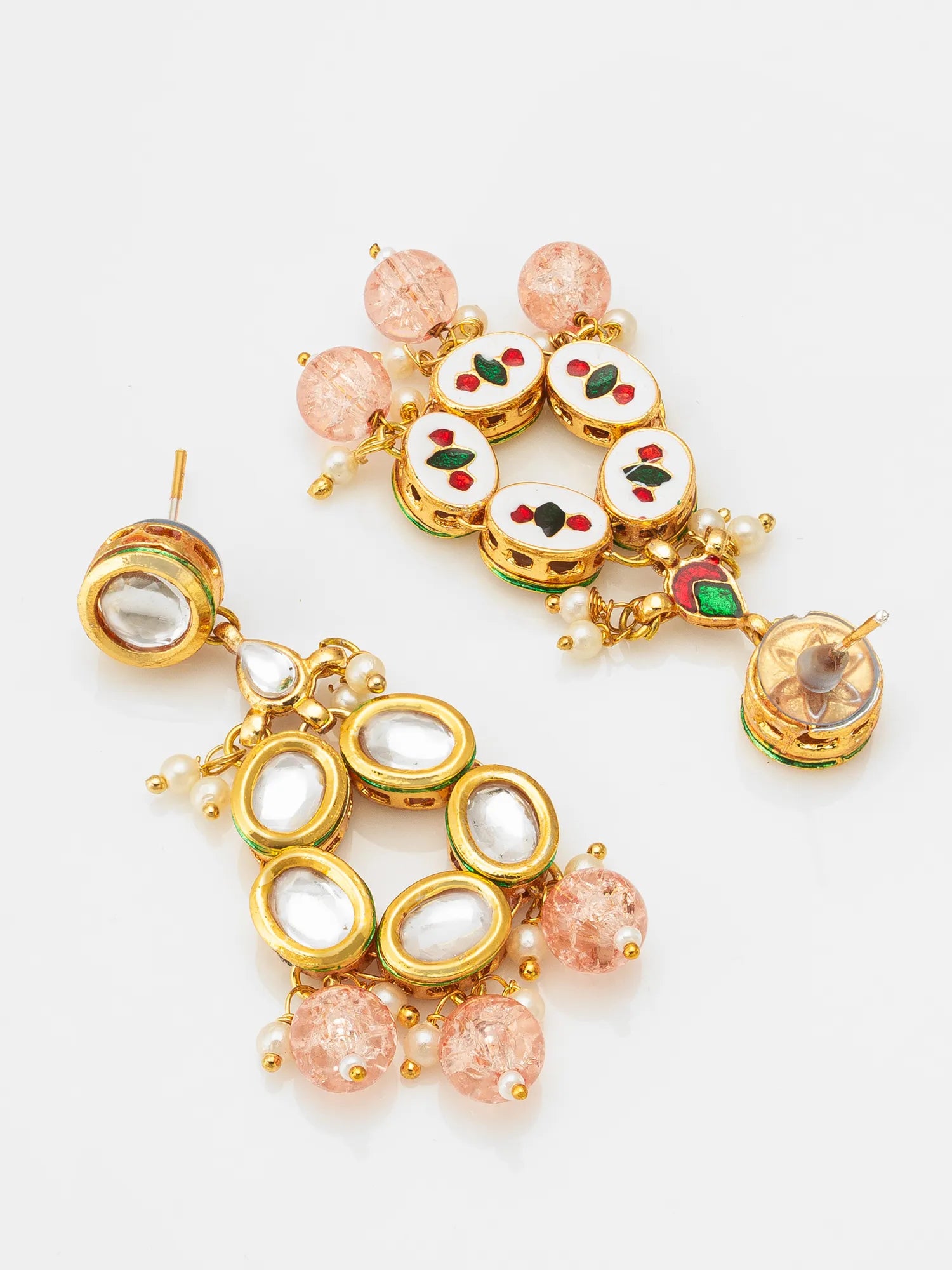 A pair of ornate gold-toned earrings with white enamel inlays, red and green floral accents, and pink faceted beads, displayed on a clean white background.