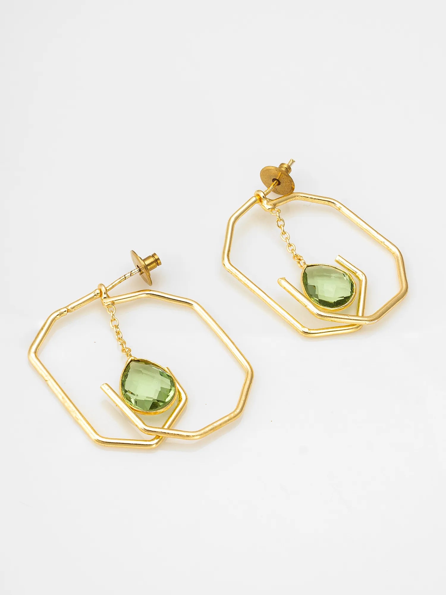 A pair of gold geometric drop earrings with faceted green gemstone charms, displayed on a clean white background.
