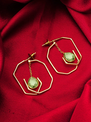 Gold geometric hoop earrings with dangling light green faceted gemstones, displayed on a draped red fabric background.