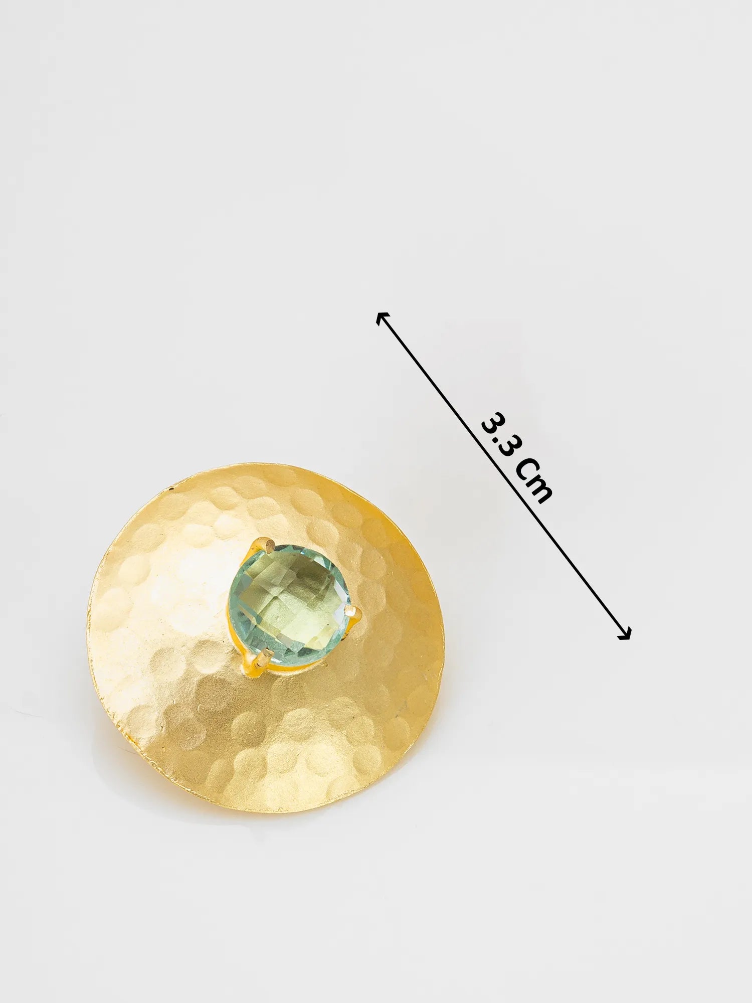 Gold circular object with a green gemstone, measurement label on a white background