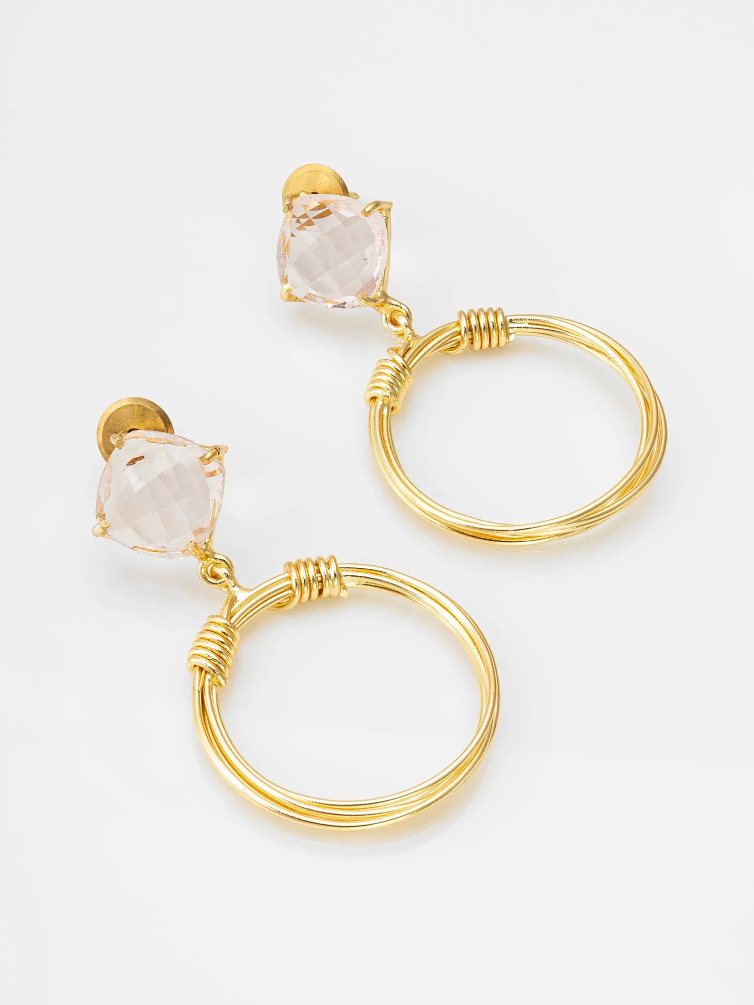 A pair of gold drop earrings featuring a small clear faceted gemstone and a larger textured gold hoop, displayed on a clean white background.