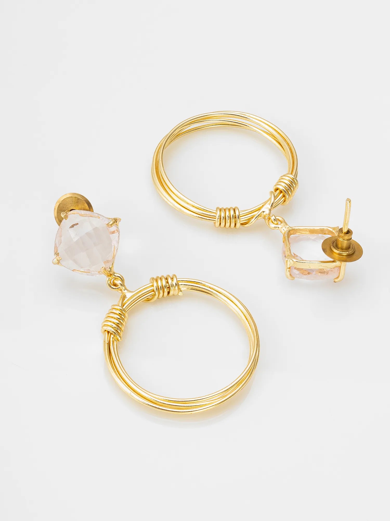 Gold-tone hoop earrings with a faceted pale pink crystal drop and a small square crystal charm, shown on a clean white background.