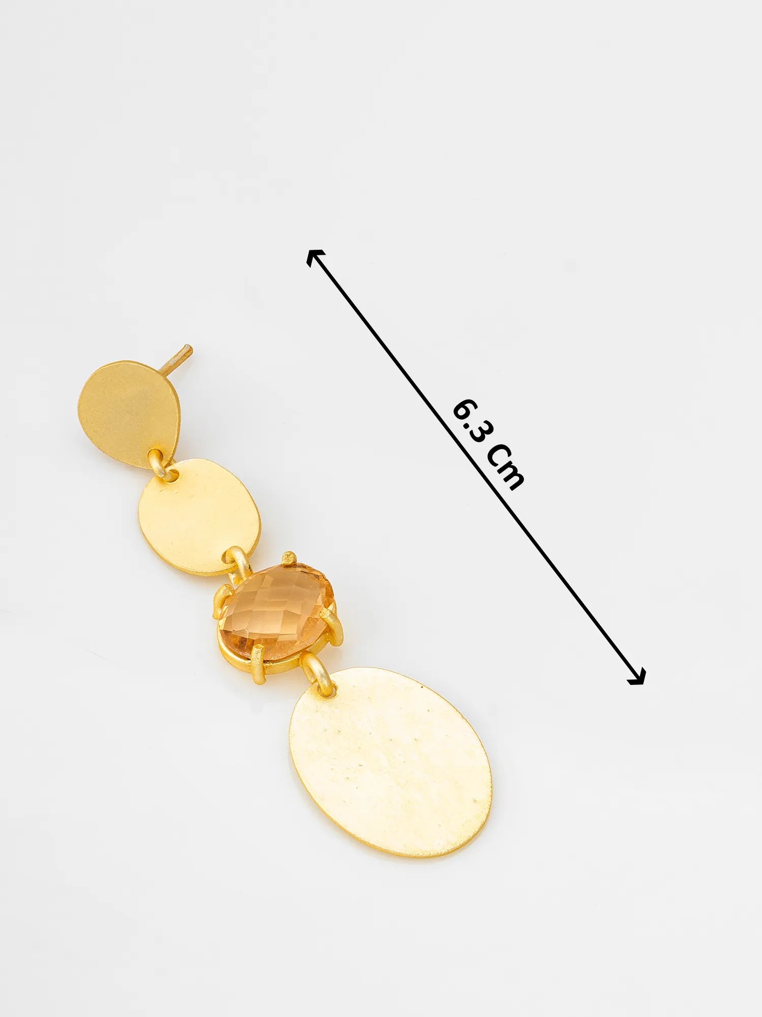 A gold-toned dangle earring with three oval disc charms and a faceted amber crystal, shown on a light gray background with a black measurement arrow and text indicating 6.3 cm length.