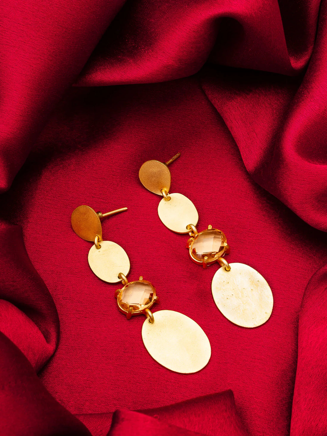 Gold earrings on a red fabric background