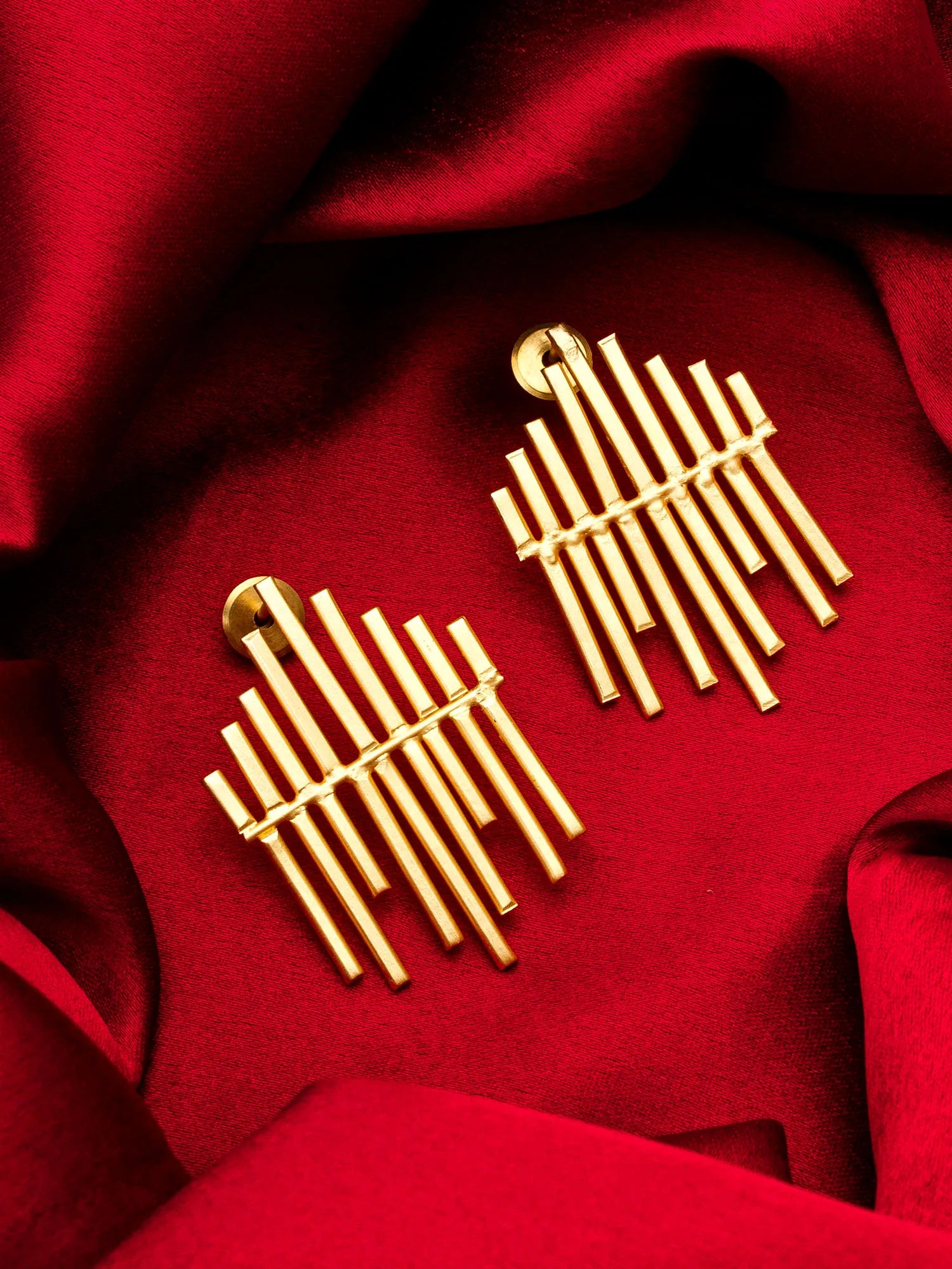 Gold earrings on a red fabric background