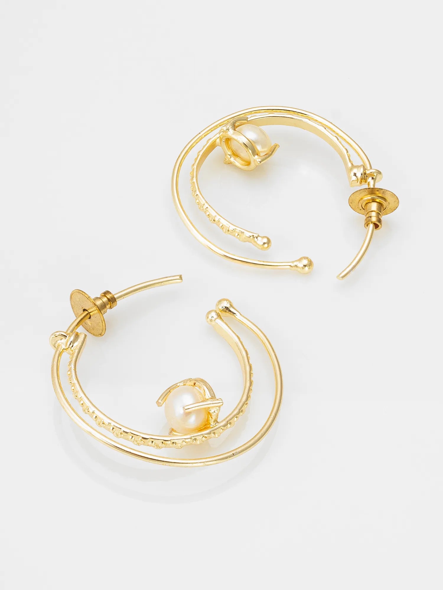 A pair of gold hoop earrings with a textured outer band, a smooth inner band, and a small white pearl accent, shown on a light gray background.