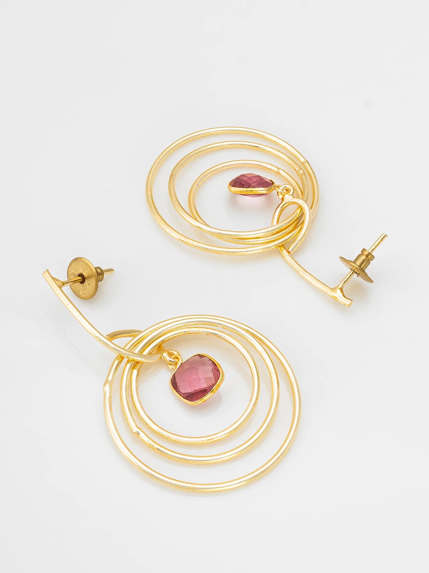 Gold hoop earrings with pink gemstones on a light gray background