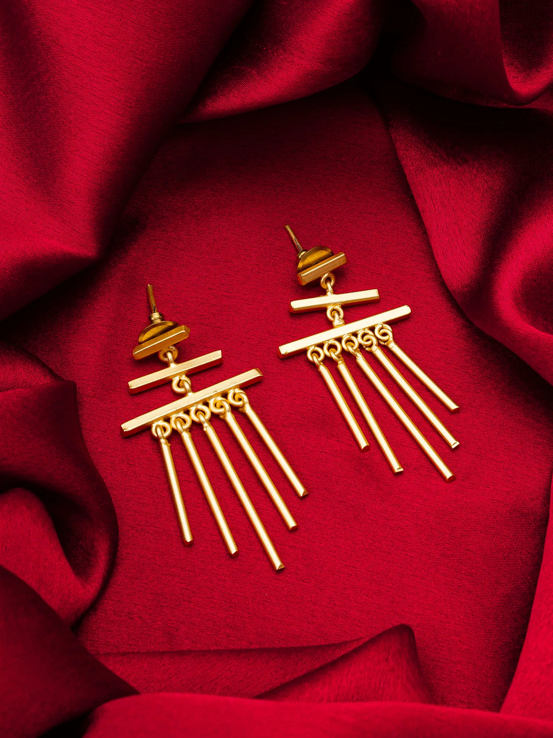 Gold earrings on a red fabric background