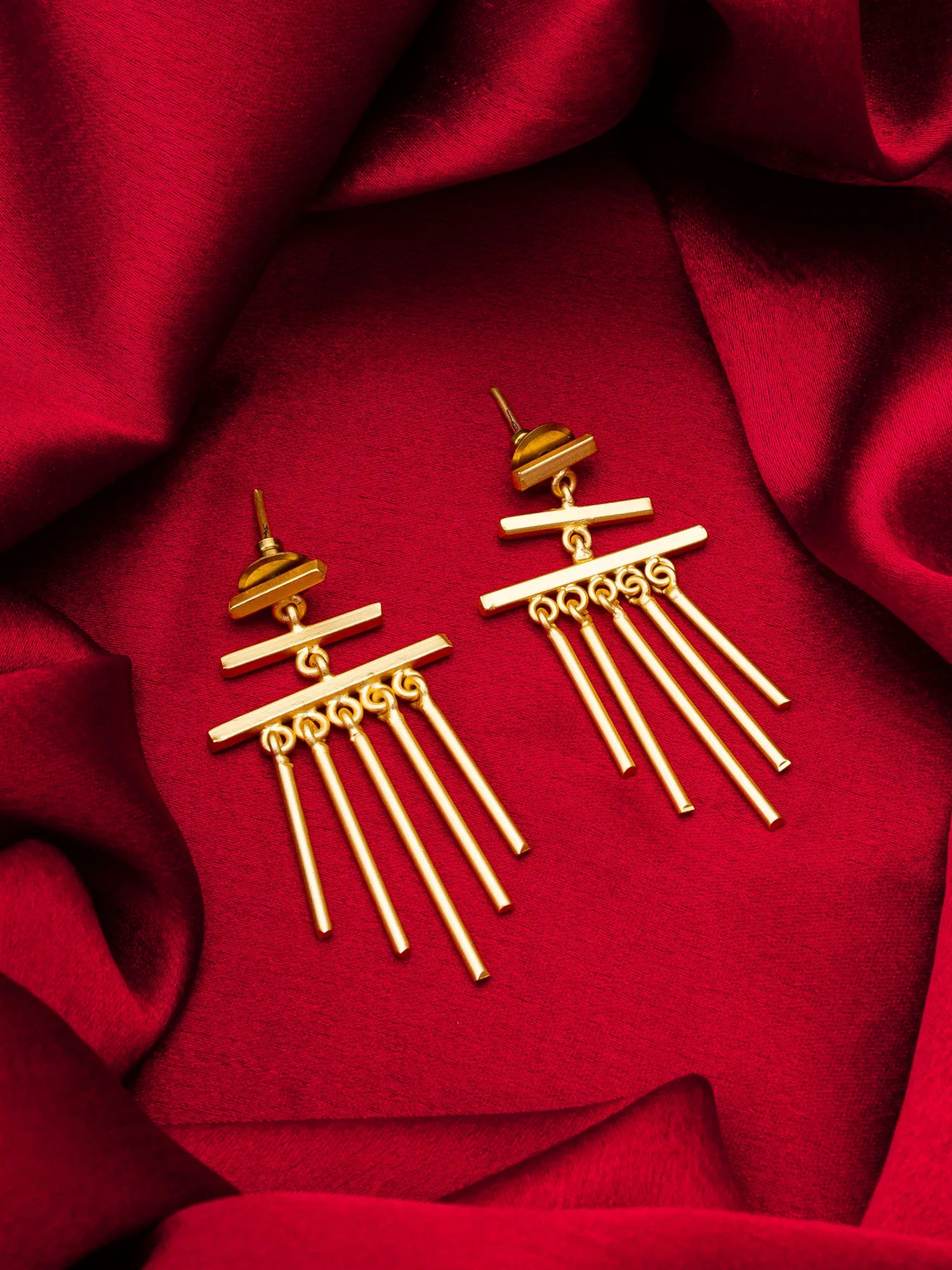Gold earrings on a red fabric background