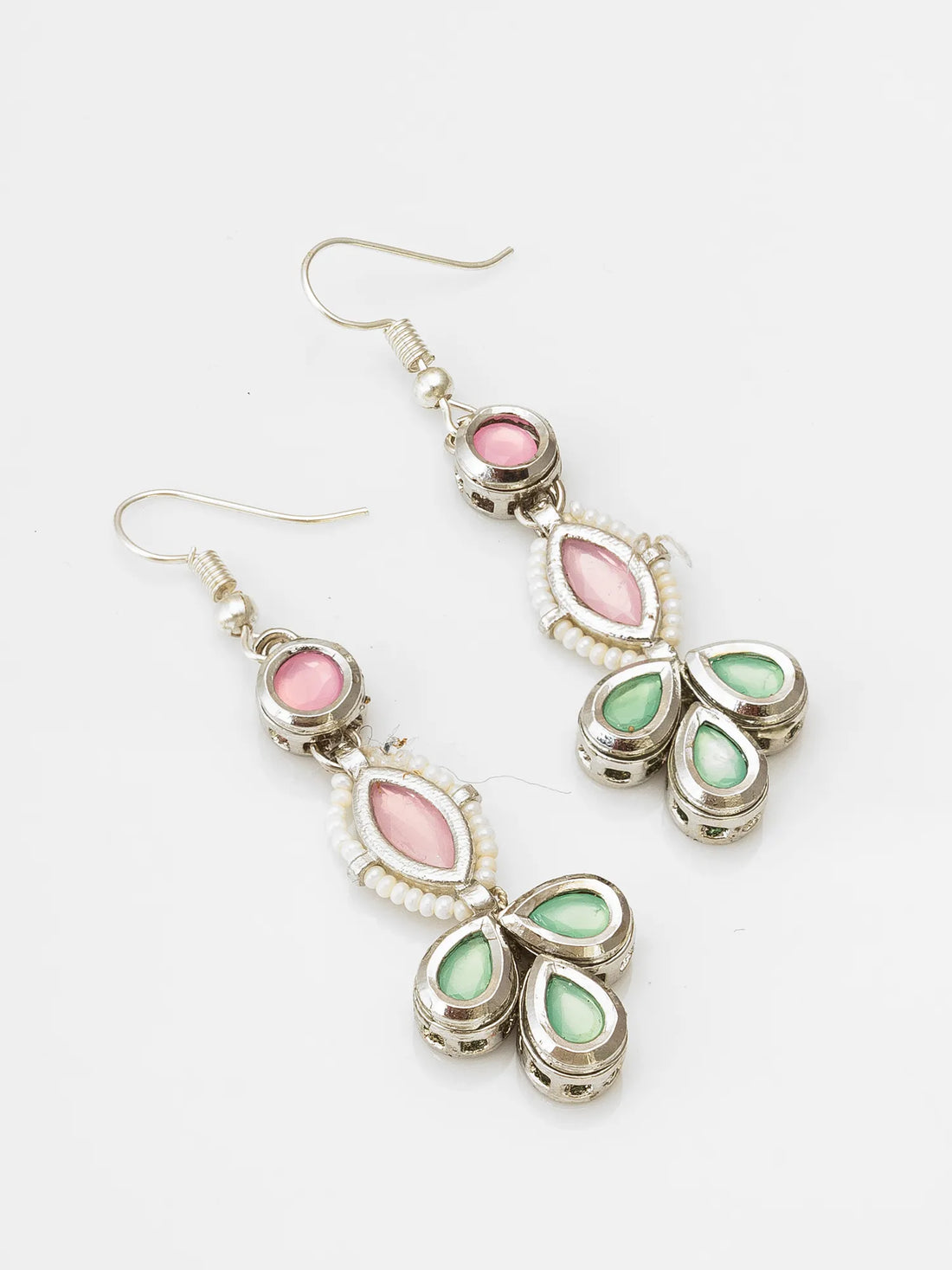 Pair of earrings with pink and green stones on a red fabric background