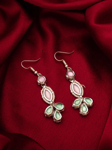 Pair of earrings with pink and green stones on a red fabric background