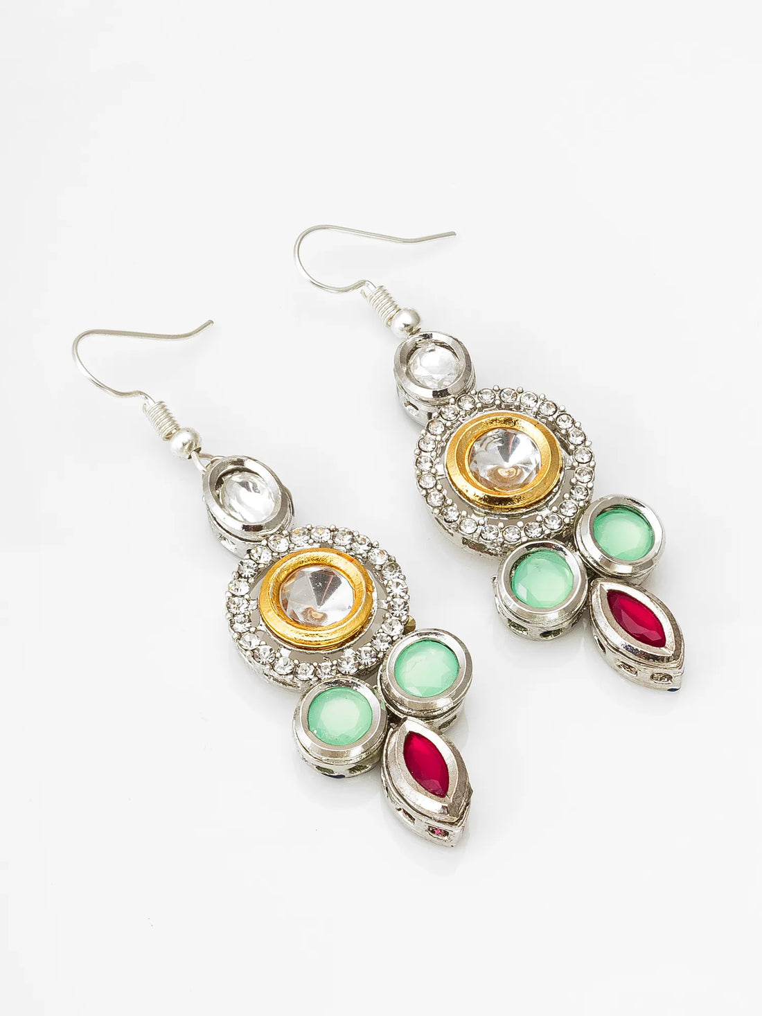 A pair of gold and silver dangle earrings with green and pink stones, displayed on a draped deep red fabric background.