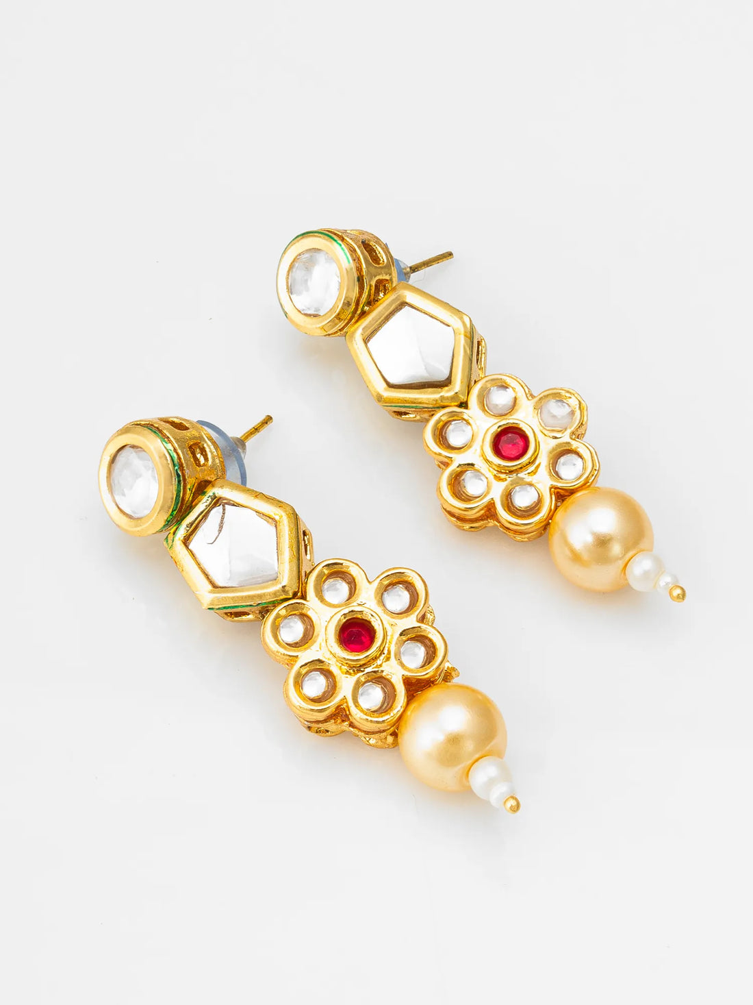 Gold earrings with pearls and red stones on a green fabric background