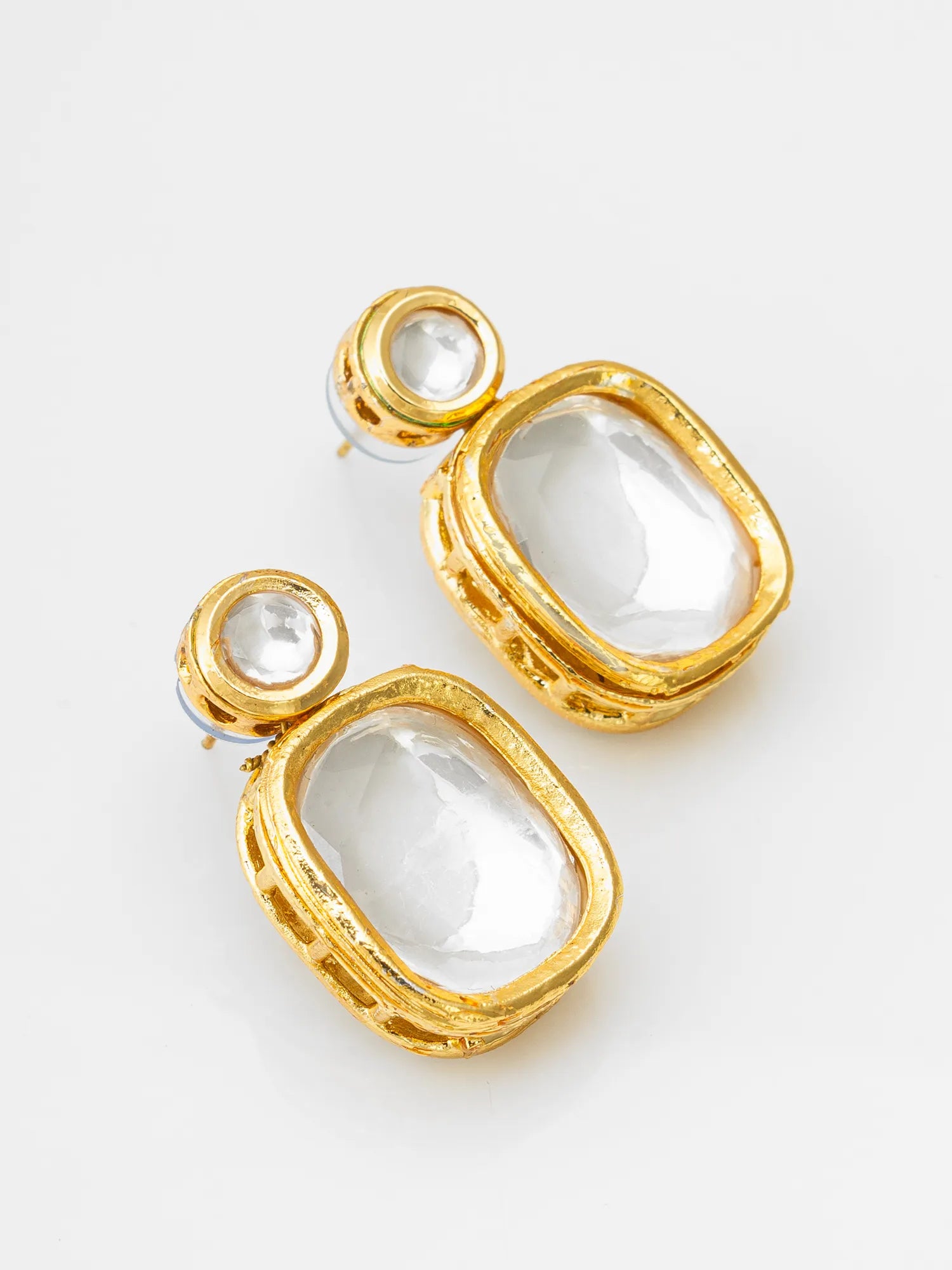 A pair of gold-plated statement earrings featuring large, bezel-set clear oval crystals and smaller round clear crystals in the top, shown on a clean white background.