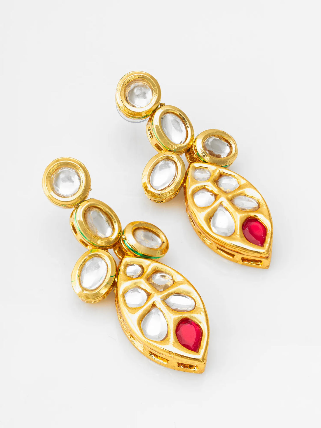 Gold earrings with red stones on a green fabric background